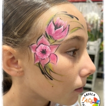 Child with a bright pink daffodil face painting design at a Tauranga event