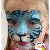 Child with a tiger face painting design at a Tauranga event, with orange
