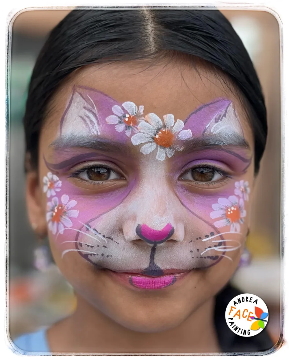 Child with a cat face painting design surrounded by daisies elements at a Tauranga event