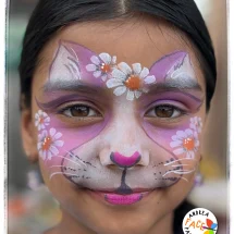 Child with a cat face painting design surrounded by daisies elements at a Tauranga event